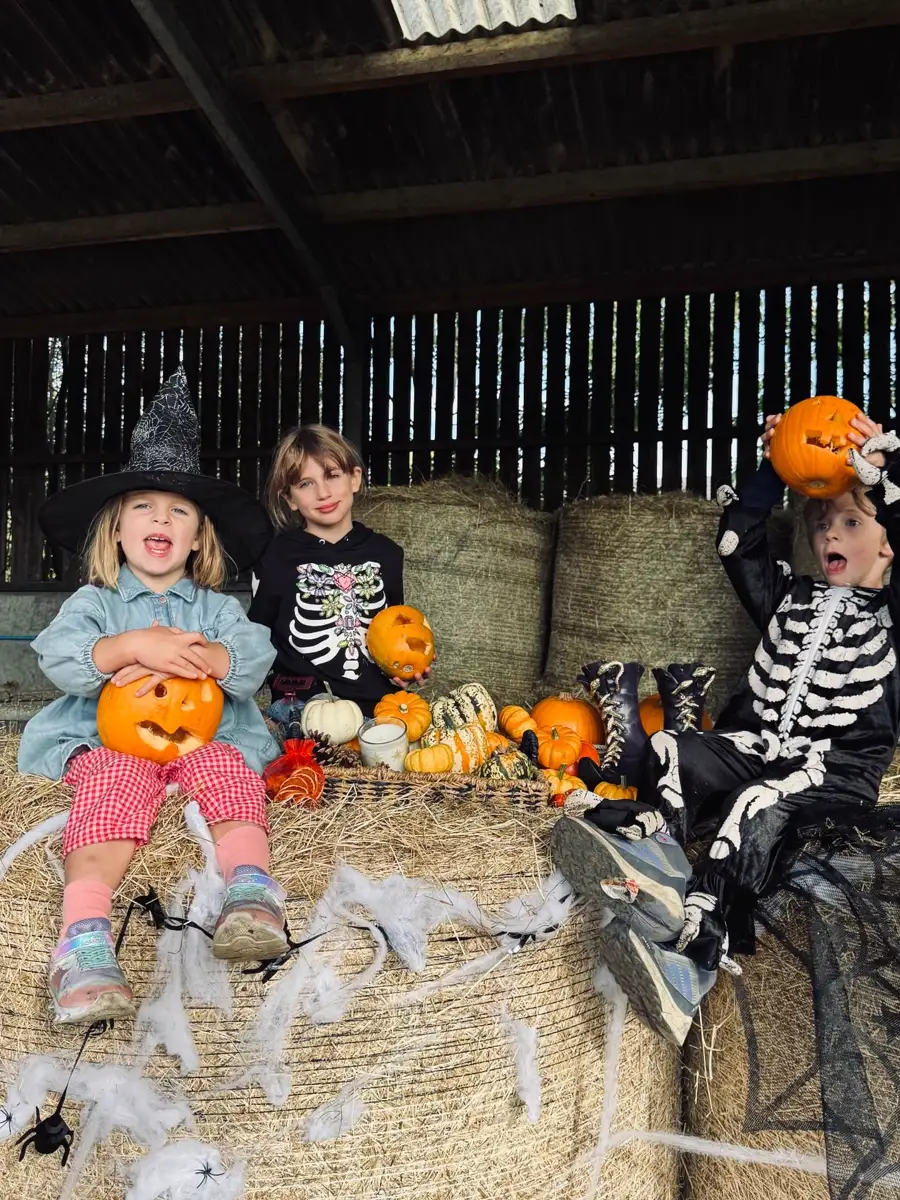 Children in costume with carved pumpkins on hay bales
