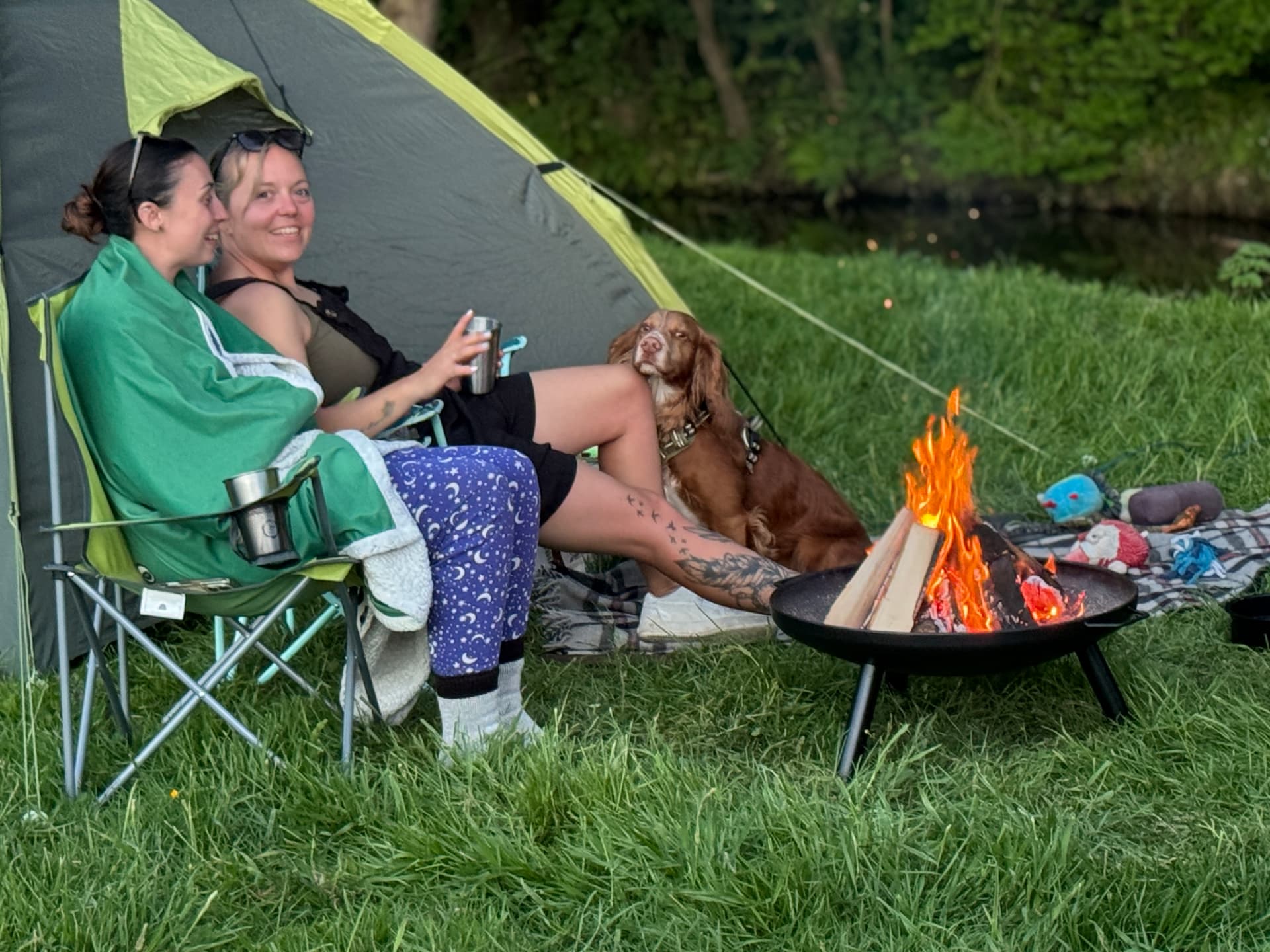 Campers beside a firepit next to the river